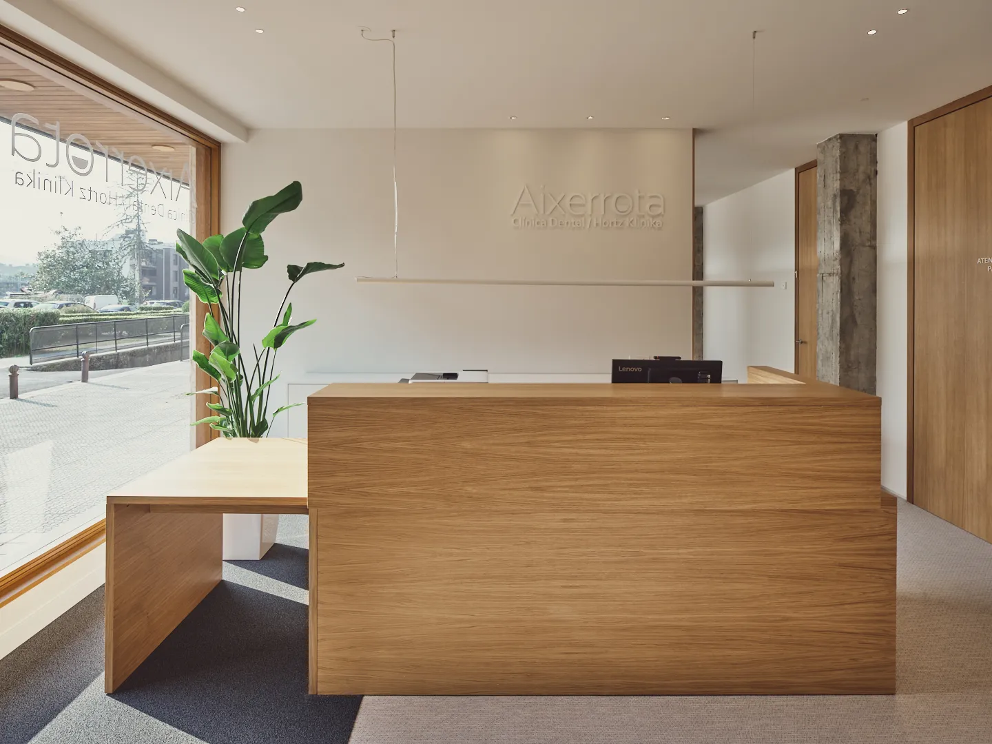 Mostrador de recepción de madera con una planta y el logotipo de Aixerrota en la pared