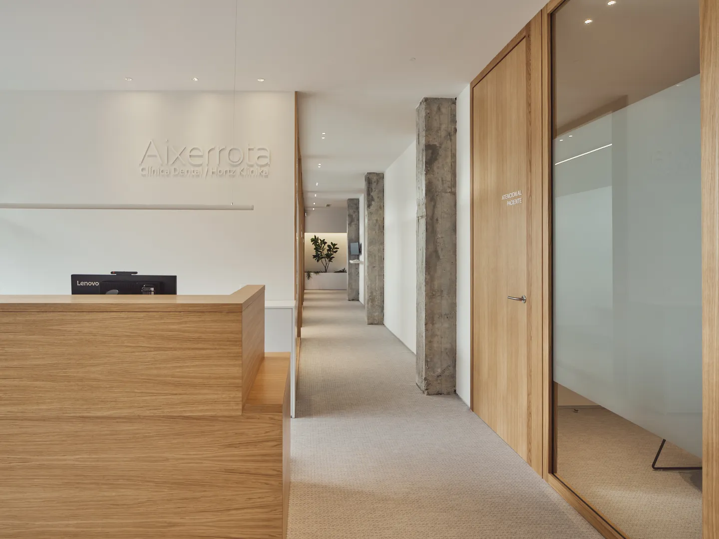 Recepción y pasillo de la clínica con puertas de madera y paredes de cristal